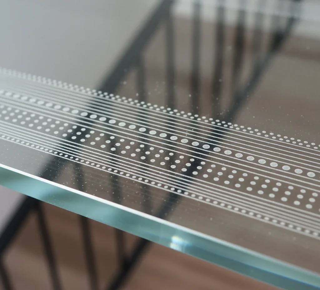 Detailaufnahme einer rutschhemmenden Oberflächenstruktur (R9) auf einer Stufe aus Glas.